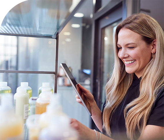 Happy salon employee doing inventory with an iPad